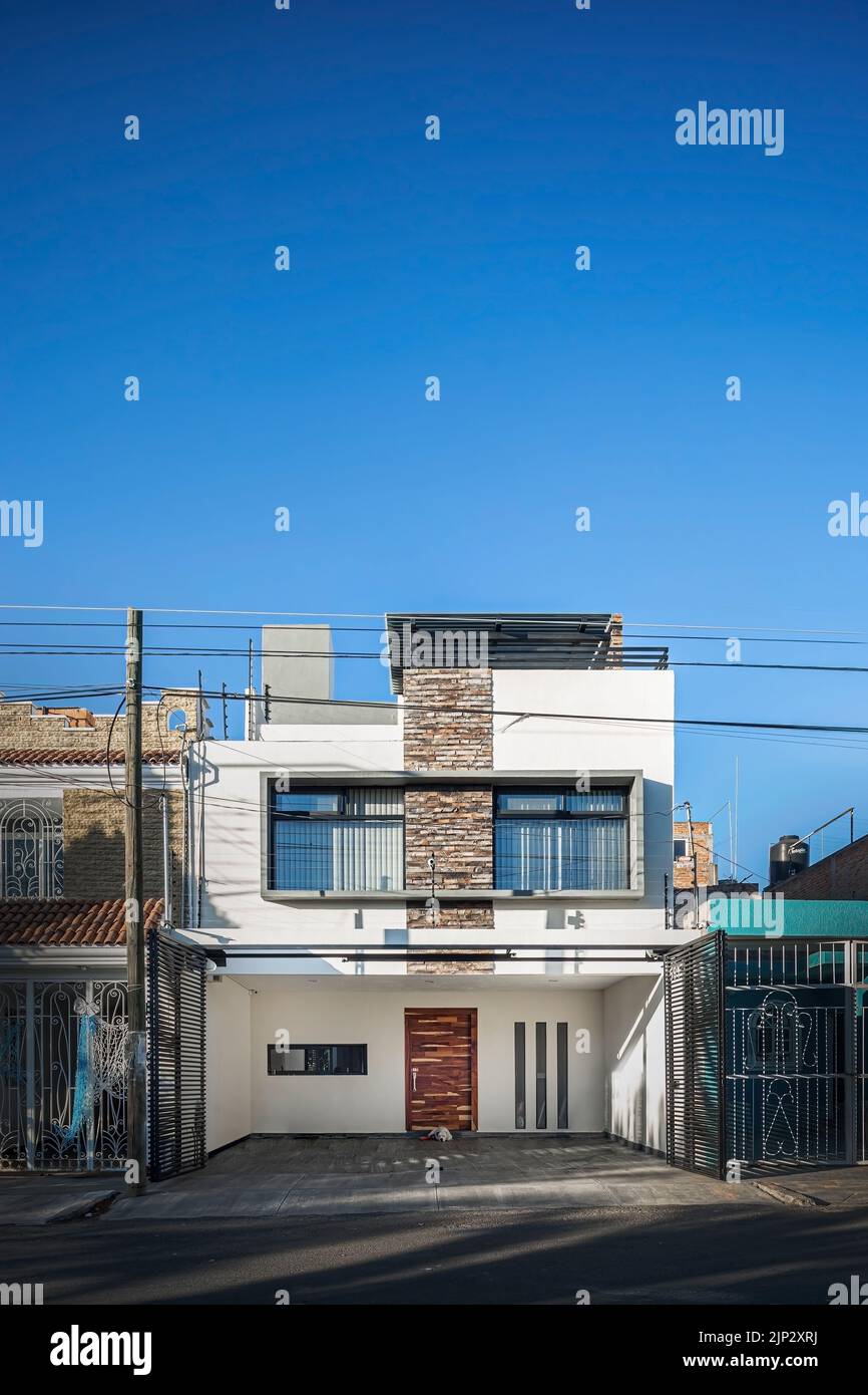 facade of a modern house with stone, staple that wraps the windows painted in gray, metal