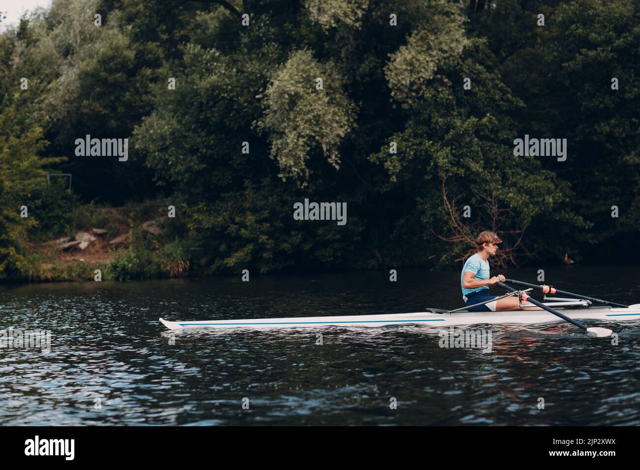 Sportsman single scull man rower rowing technique on boat. Paddle oar