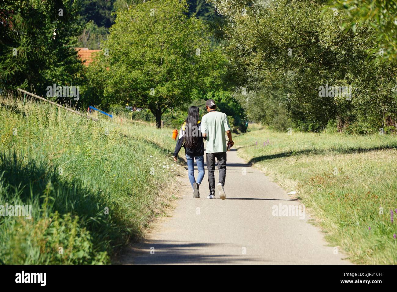 A young dark-skinned couple walking in the green park along the Neckar in Heidelberg Stock Photo