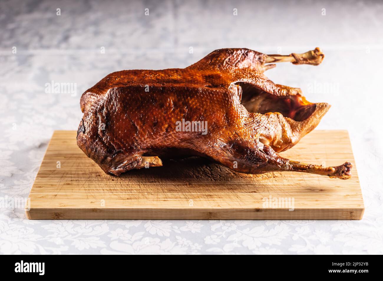 Portioned roast goose on a wooden cutting board - Close up. Stock Photo