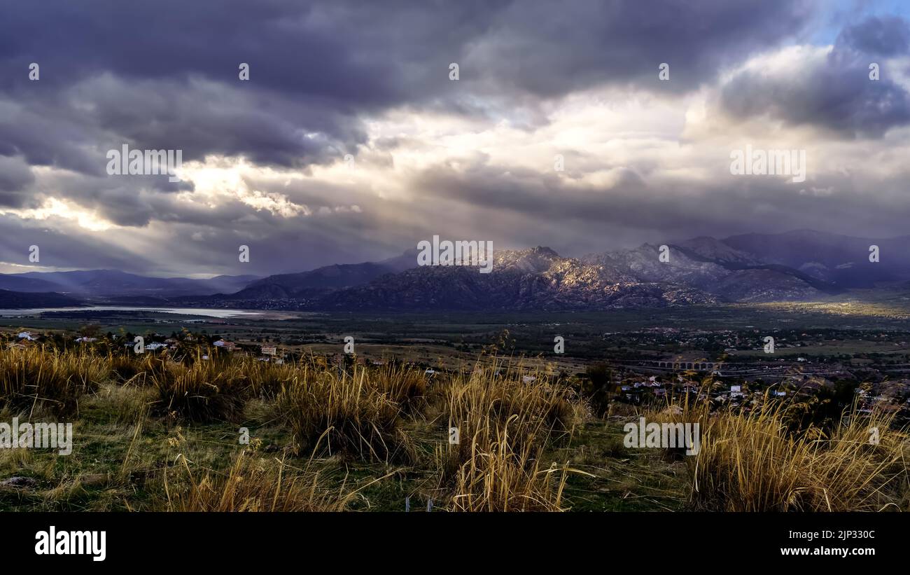 Dramatic storm sky landscape with sun rays between the clouds and over the mountains. Dark landscape. Madrid. Stock Photo