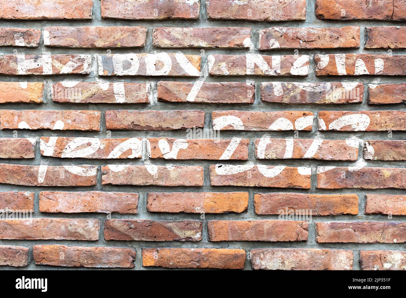 A graffiti with white ink wishing happy new year 2023 on a brick wall