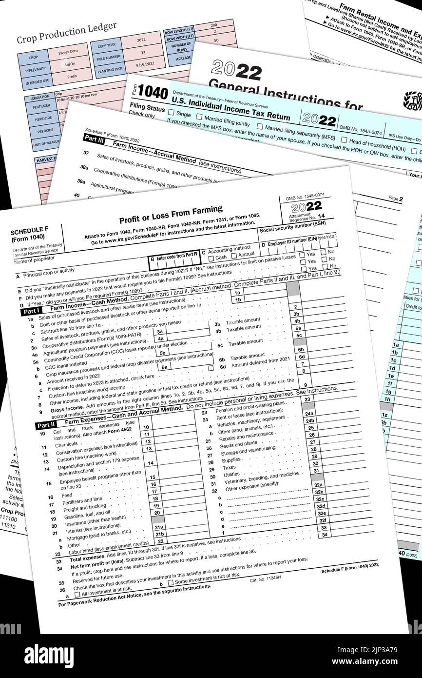 2022 IRS 1040 and farm tax forms with a simulated crop production page on a black desktop. Stock Photo