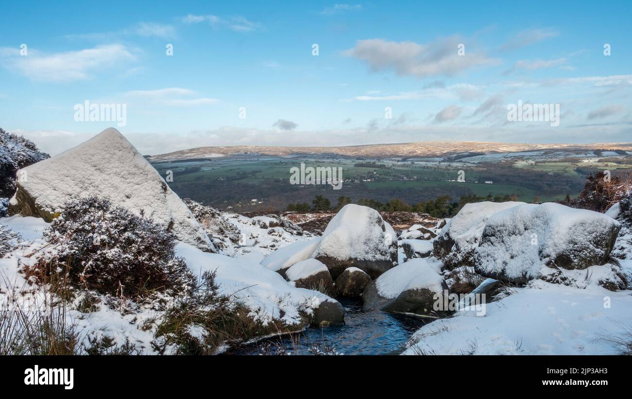 UK Landscapes: Snow at the iconic tourist attraction of Ilkley Moor with snowy rocks in next to Backstone Beck, West Yorkshire, England, UK Stock Photo