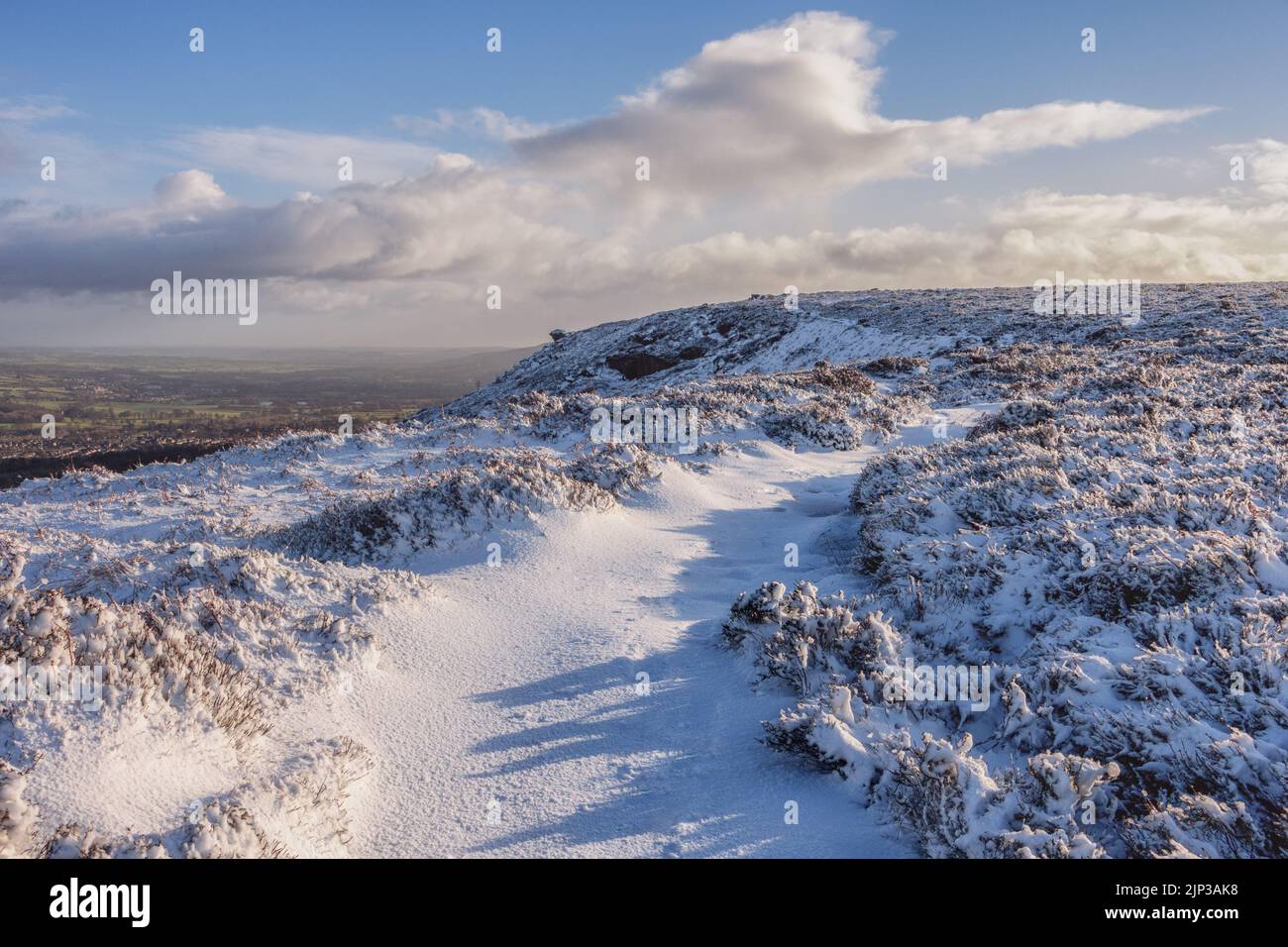UK Landscapes: Snow at the iconic tourist attraction of Ilkley Moor with the Pancake Stone ahead following the snowy path, West Yorkshire, England, UK Stock Photo