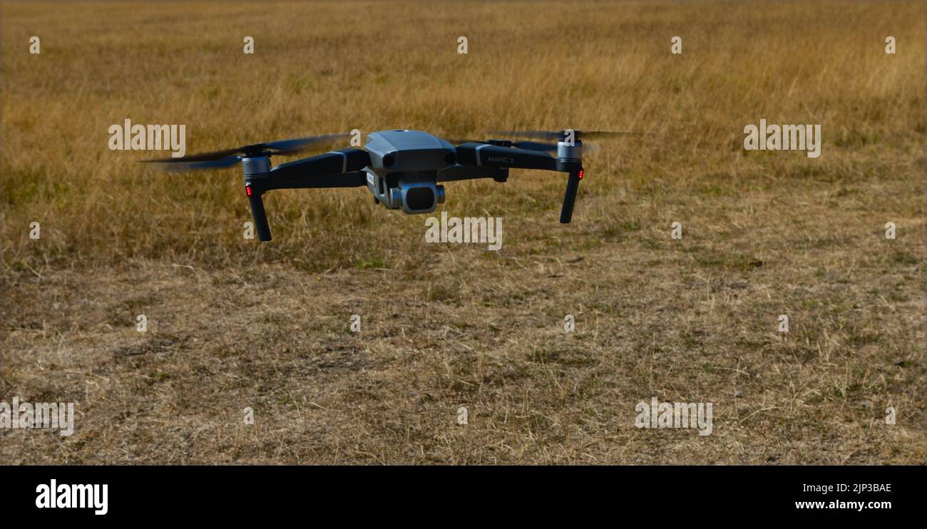 DJI Mavic 2 Pro drone flying low over parched grass Stock Photo