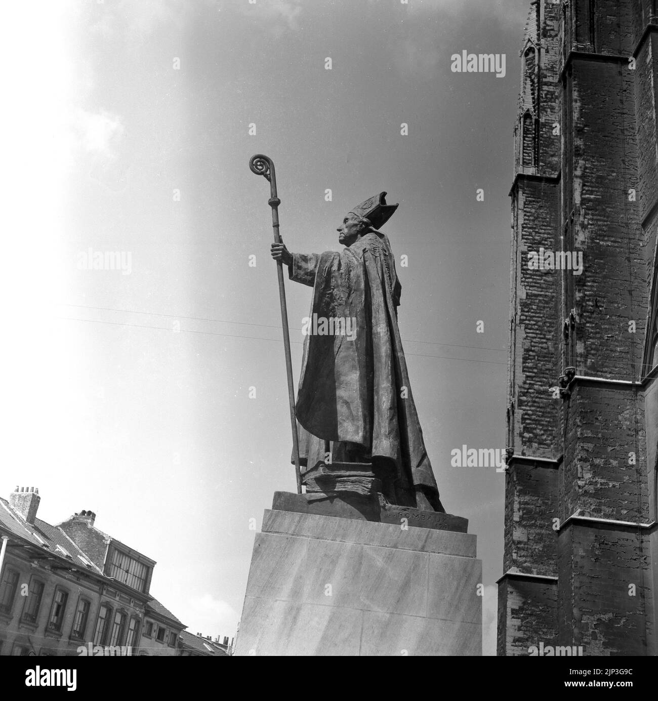 1960, historical, side view, from below, of a statute by Égide Rombaux of catholic priest Cardinal Mercier outside St. Michael and Gudula Cathedral, Brussels, Belgium. E. Rombaux, 1941 is inscribed on the base.  The statue shows the Cardinal in full dress carrying a staff, a crosier, with a curved top that is a symbol of the Good Shepherd. Desire-Joseph Mericer was known for his fierce resistance to the German occupation of the country during WW1, and as a noted scholar, distributed a letter, Patriotism and Endurance, after the invasion to be read in all his churches. Stock Photo