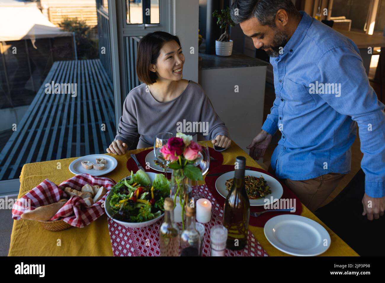 Happy diverse couple sitting at table, eating dinner together Stock Photo