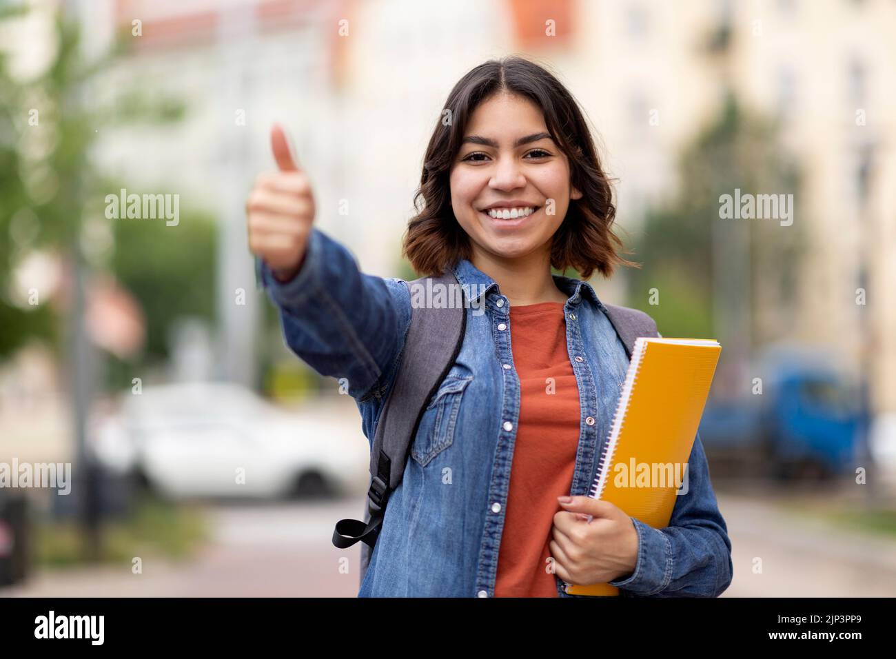 Smiling Arab Female Student Showing Thumb Up At Camera While Posing Outdoors Stock Photo