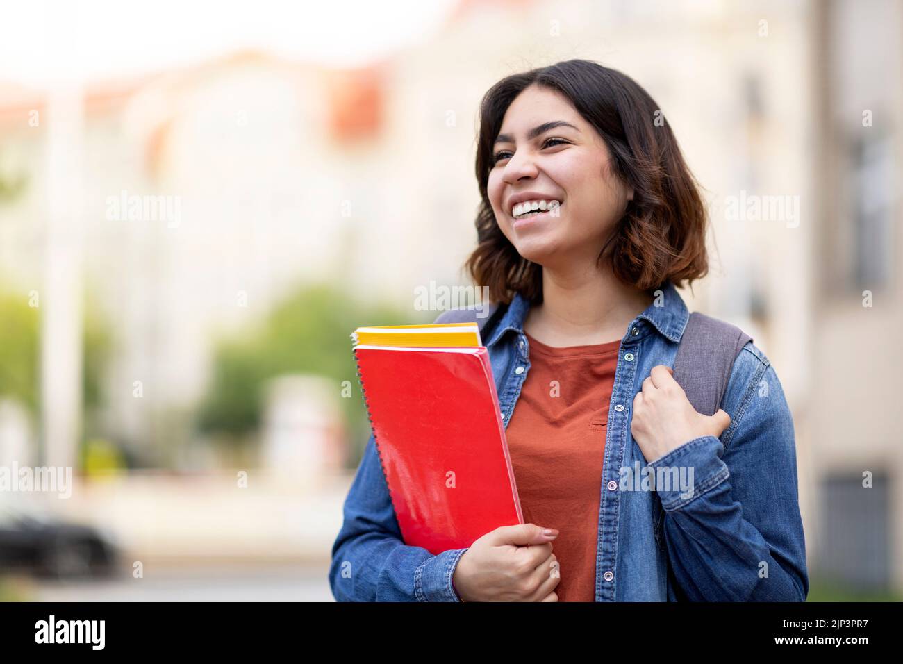 Portrait Of Beautiful Arab Female Student With Workbooks In Hand Posing Outdoors Stock Photo