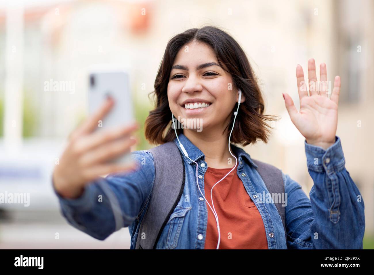 Happy young arab woman making video call via cellphone while standing outdoors Stock Photo