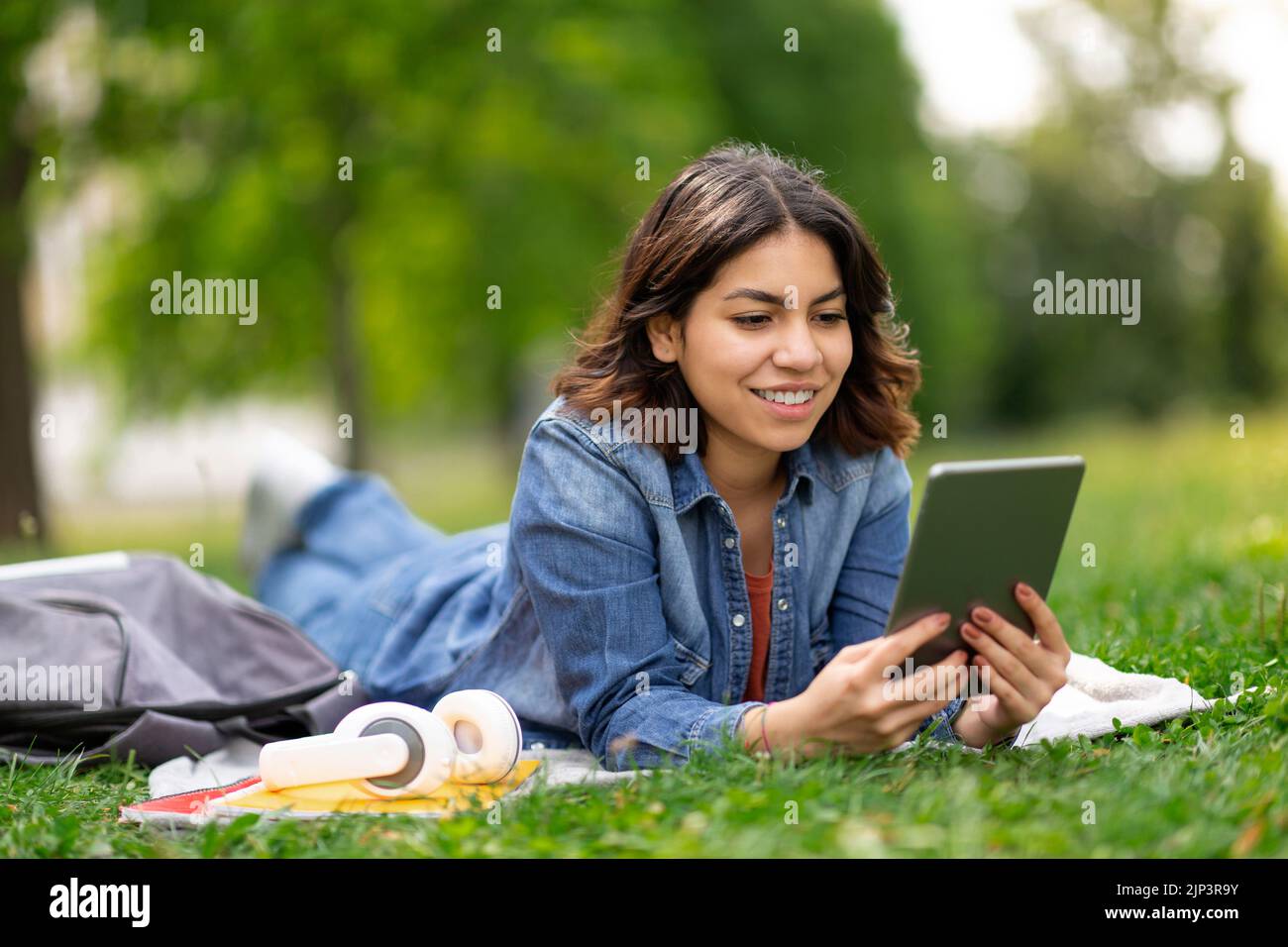 Beautiful Young Arab Woman Relaxing With Digital Tablet On Lawn In Park Stock Photo