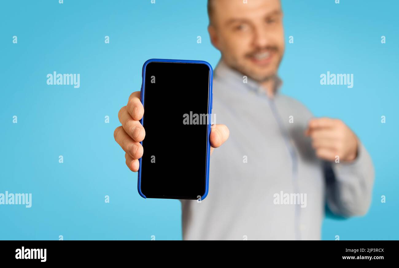 Man Advertising Mobile Offer Showing Smartphone Screen On Blue Background Stock Photo