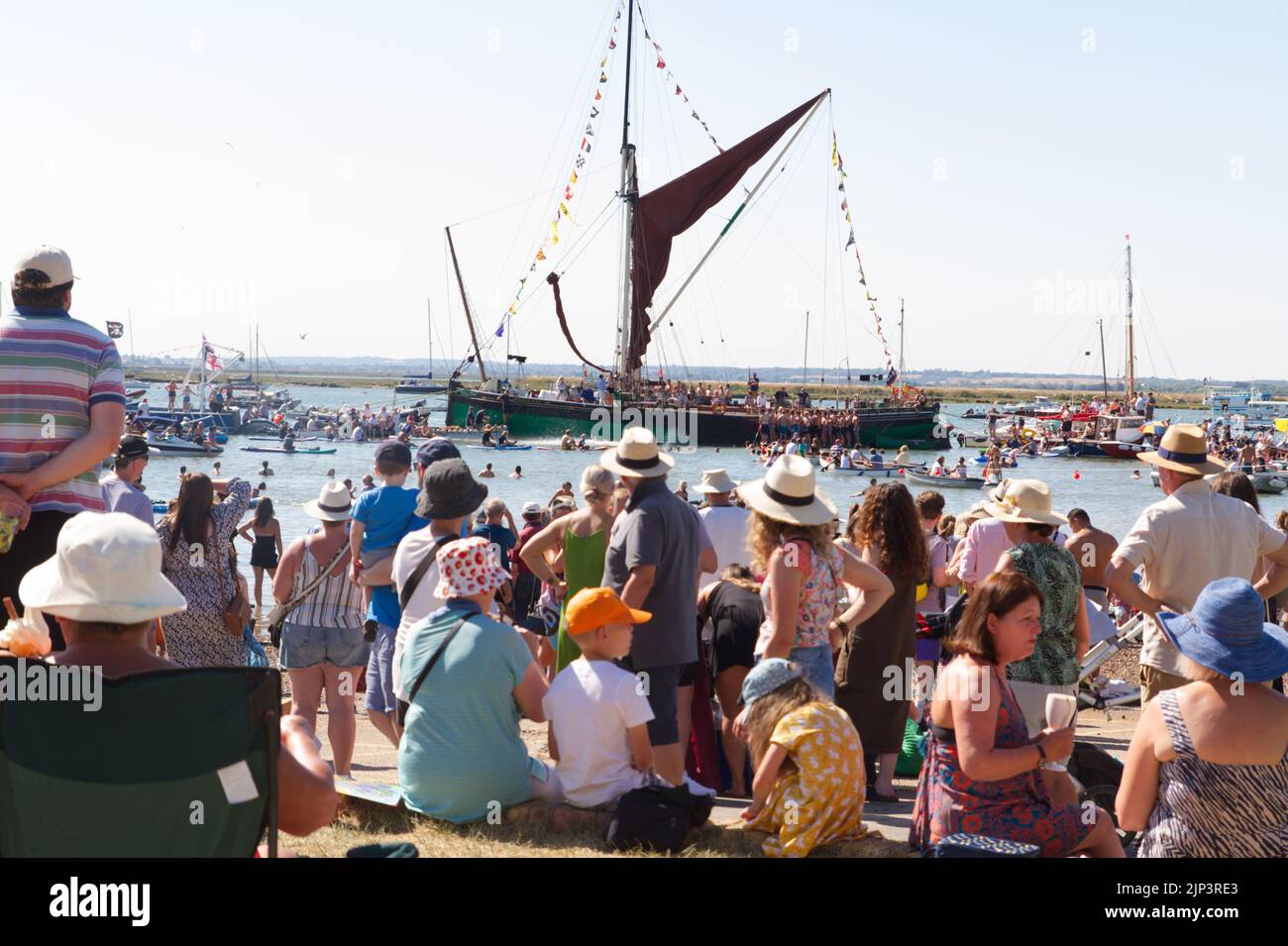 West Mersea Town Regatta on Mersea Island in Essex. Crowds enjoying the sunshine as they look out towards the Thames Barge 'Kitty'. Stock Photo