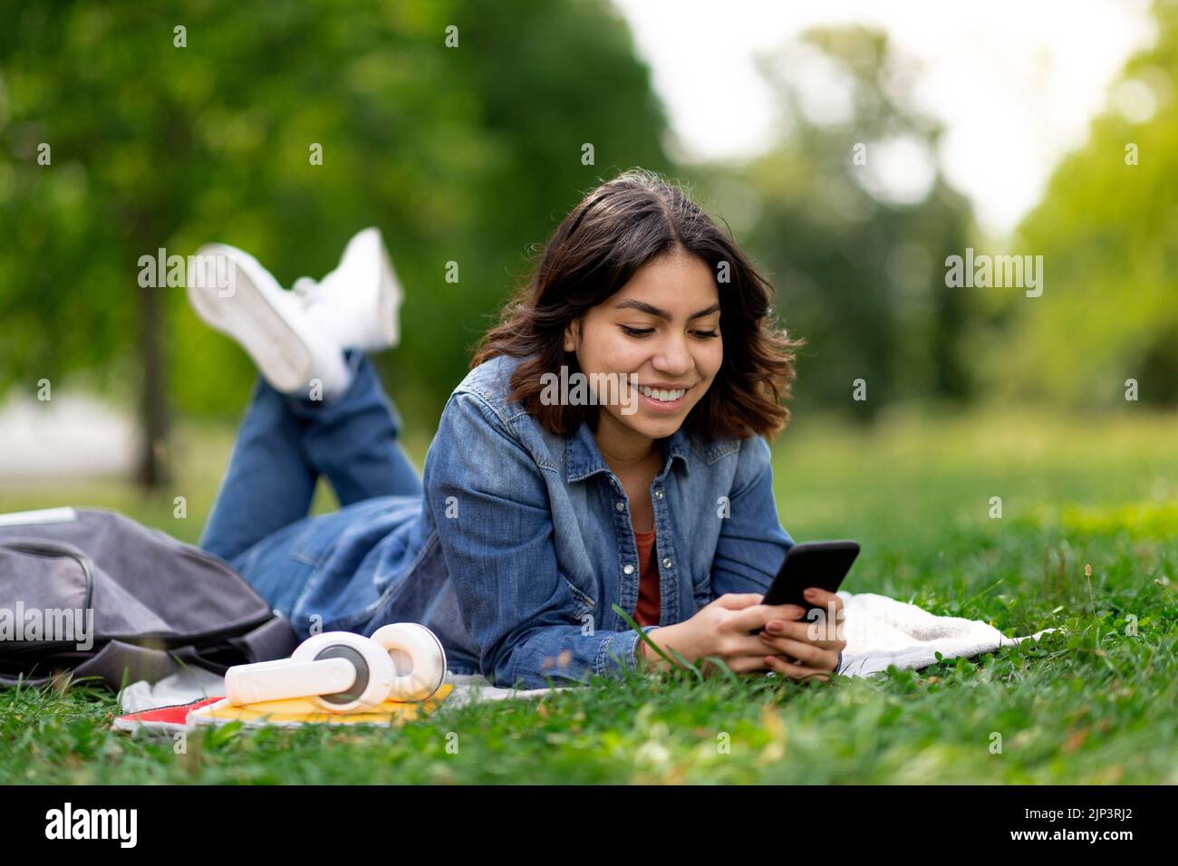 Portrait Of Beautiful Young Arab Woman Relaxing In Park With Smartphone Stock Photo