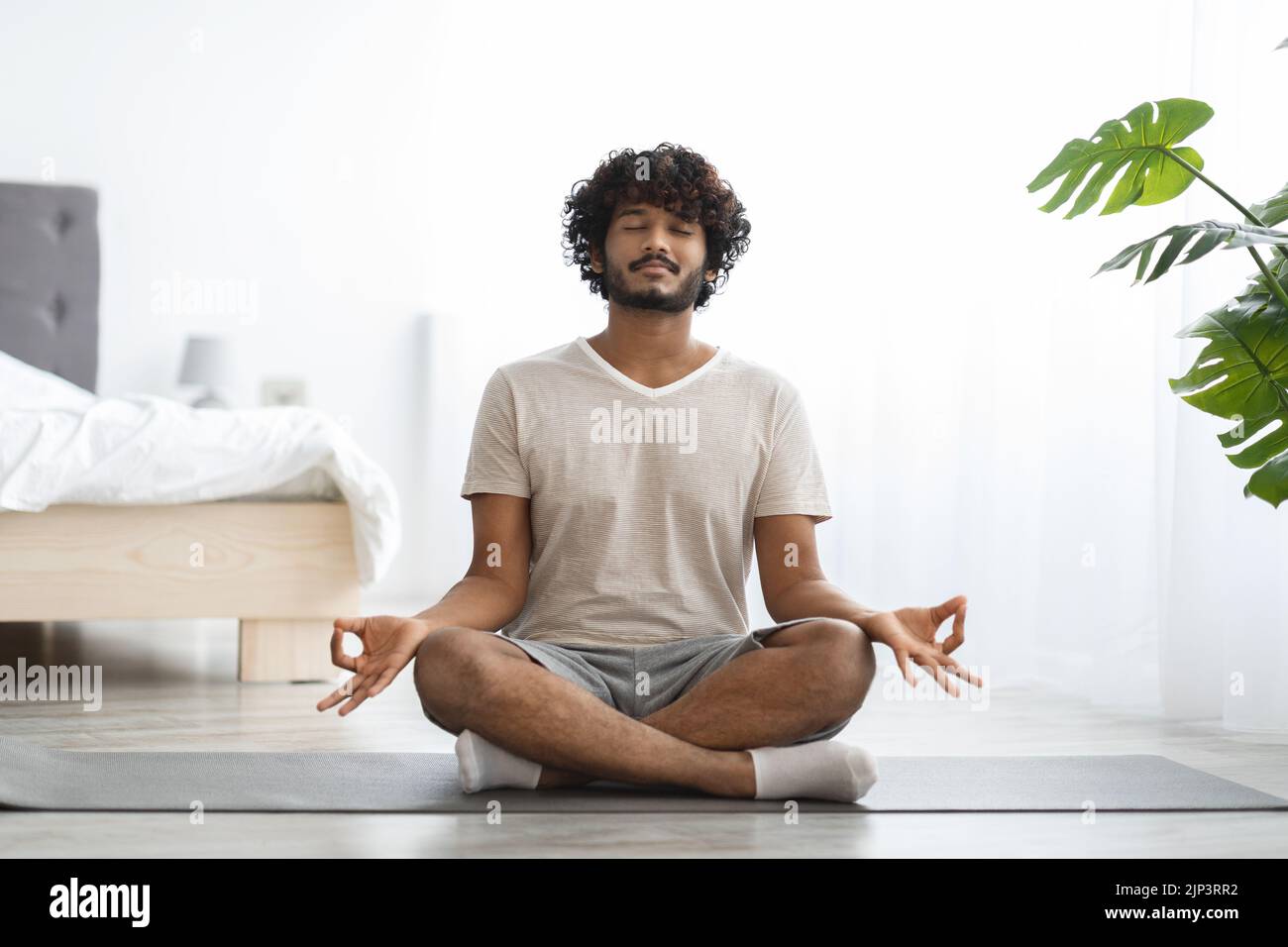 Peaceful indian man practicing yoga at home, meditating Stock Photo