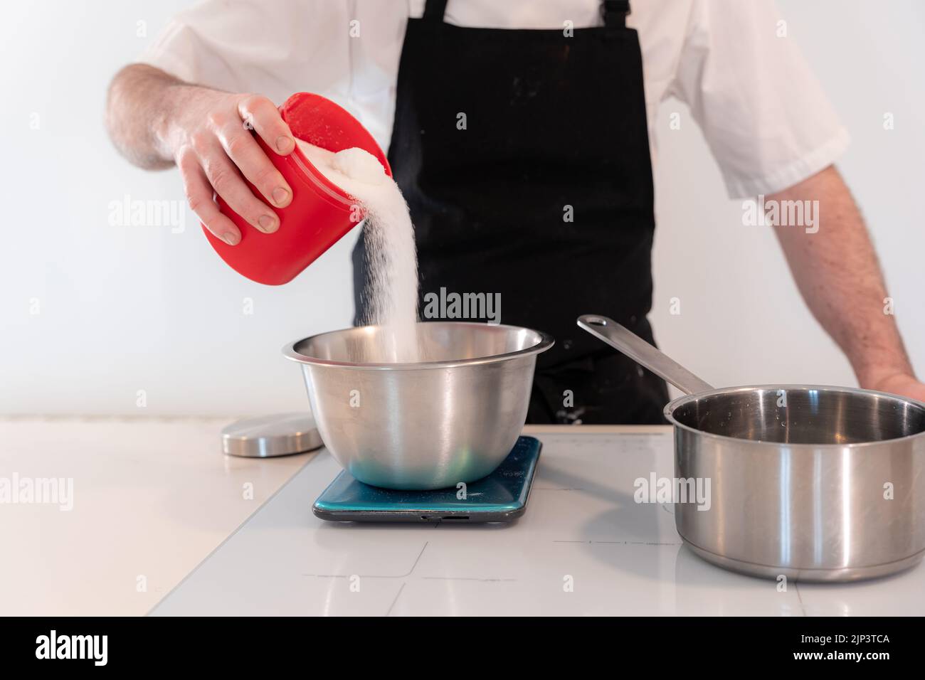 A closeup of a man cooking a red velvet cake, preparing Swiss meringue