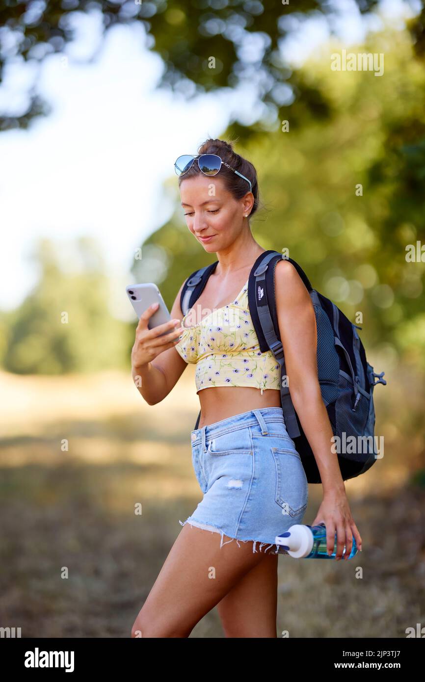 Woman walking outdoors looking at her phone Stock Photo