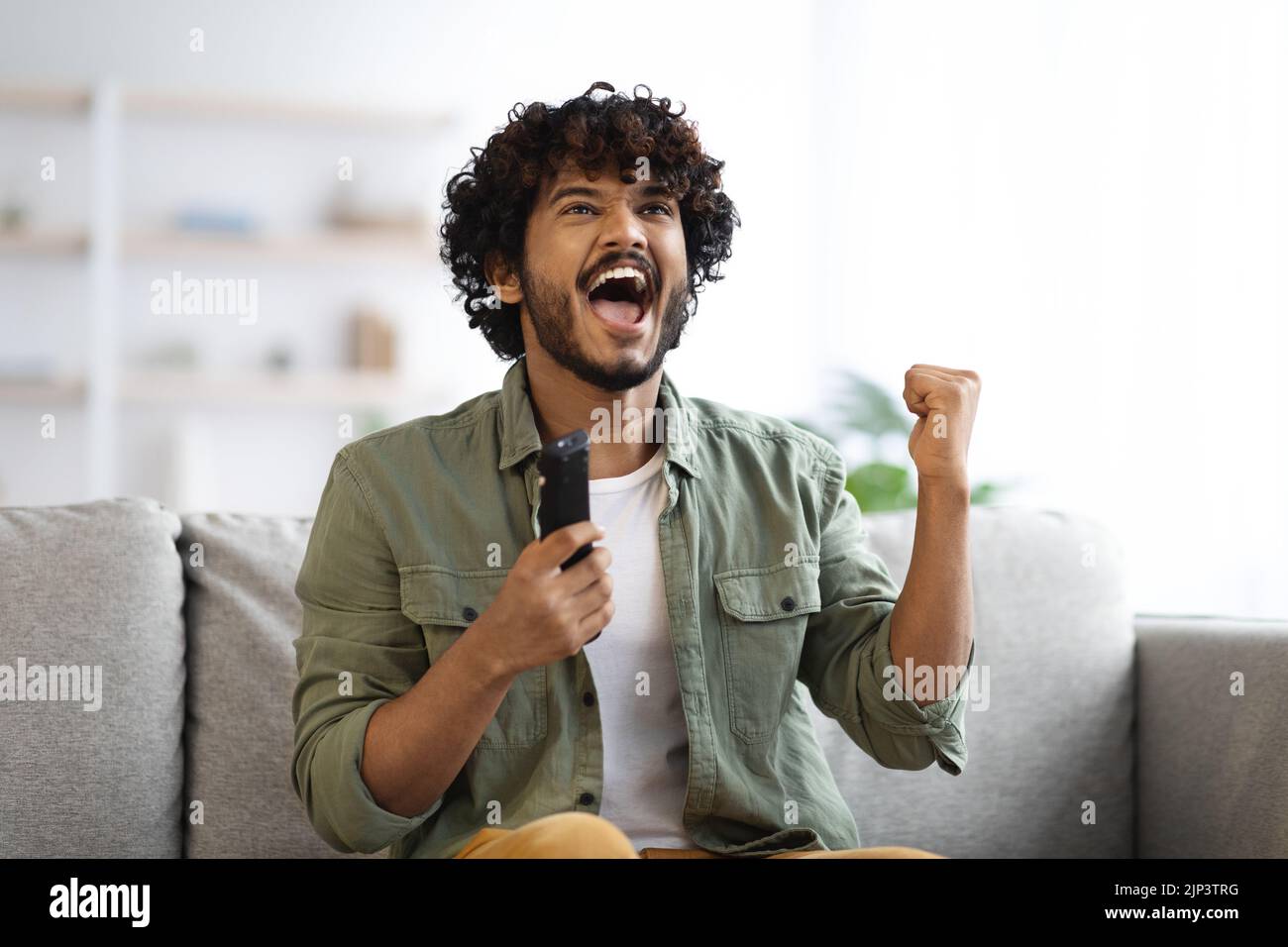 Indian man cheering at football game on television at home Stock Photo