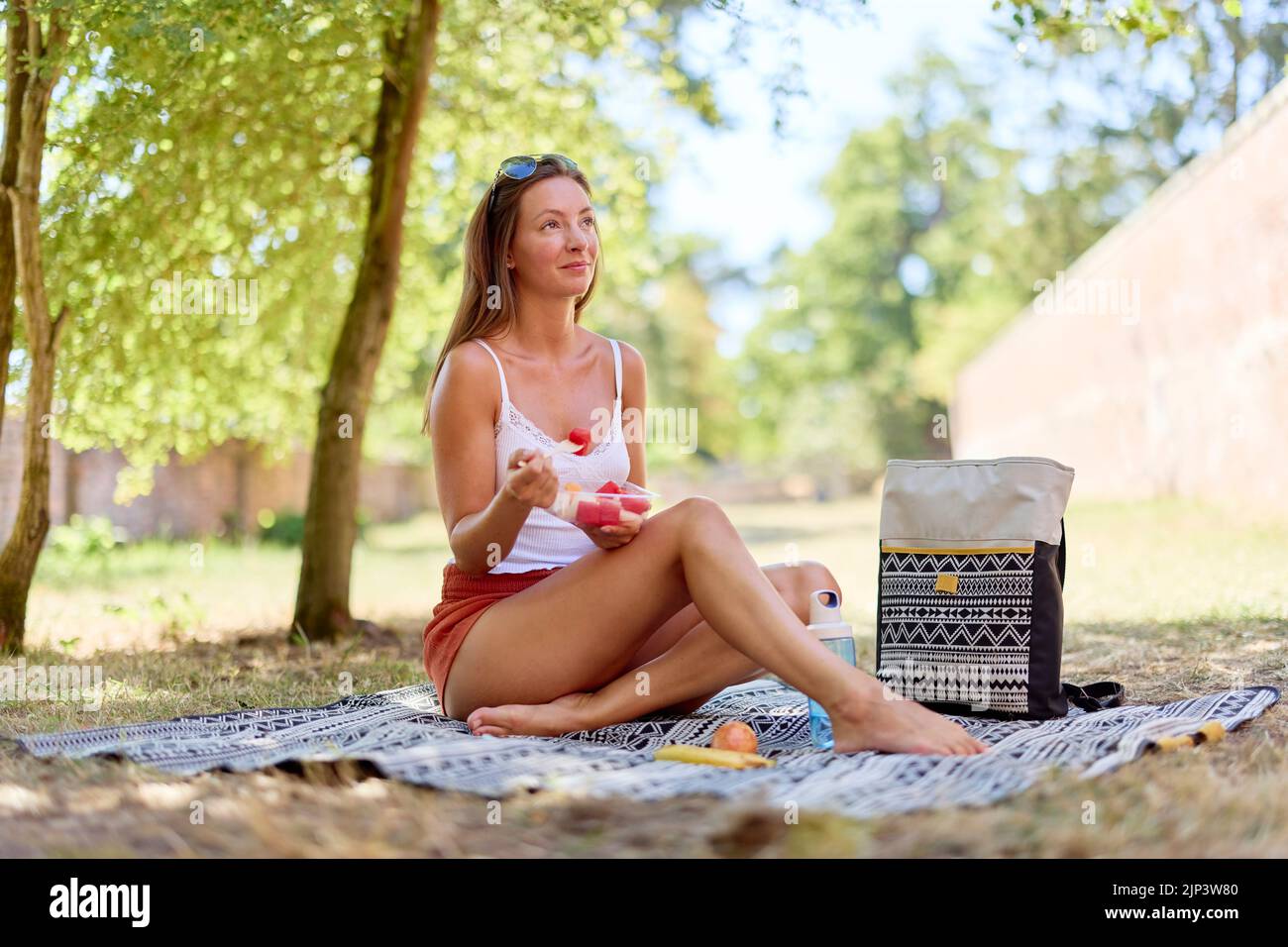 Woman sat relaxing eating fresh fruit outdoors Stock Photo