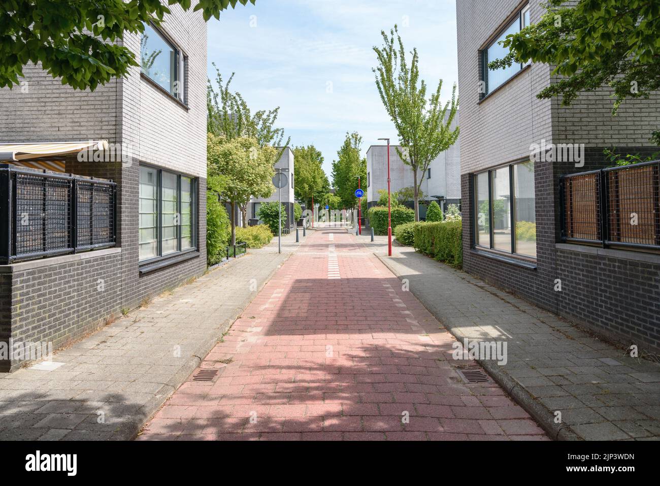 Empty stone bicycle lane between modern brick houses in housing development on a sunny summer day Stock Photo