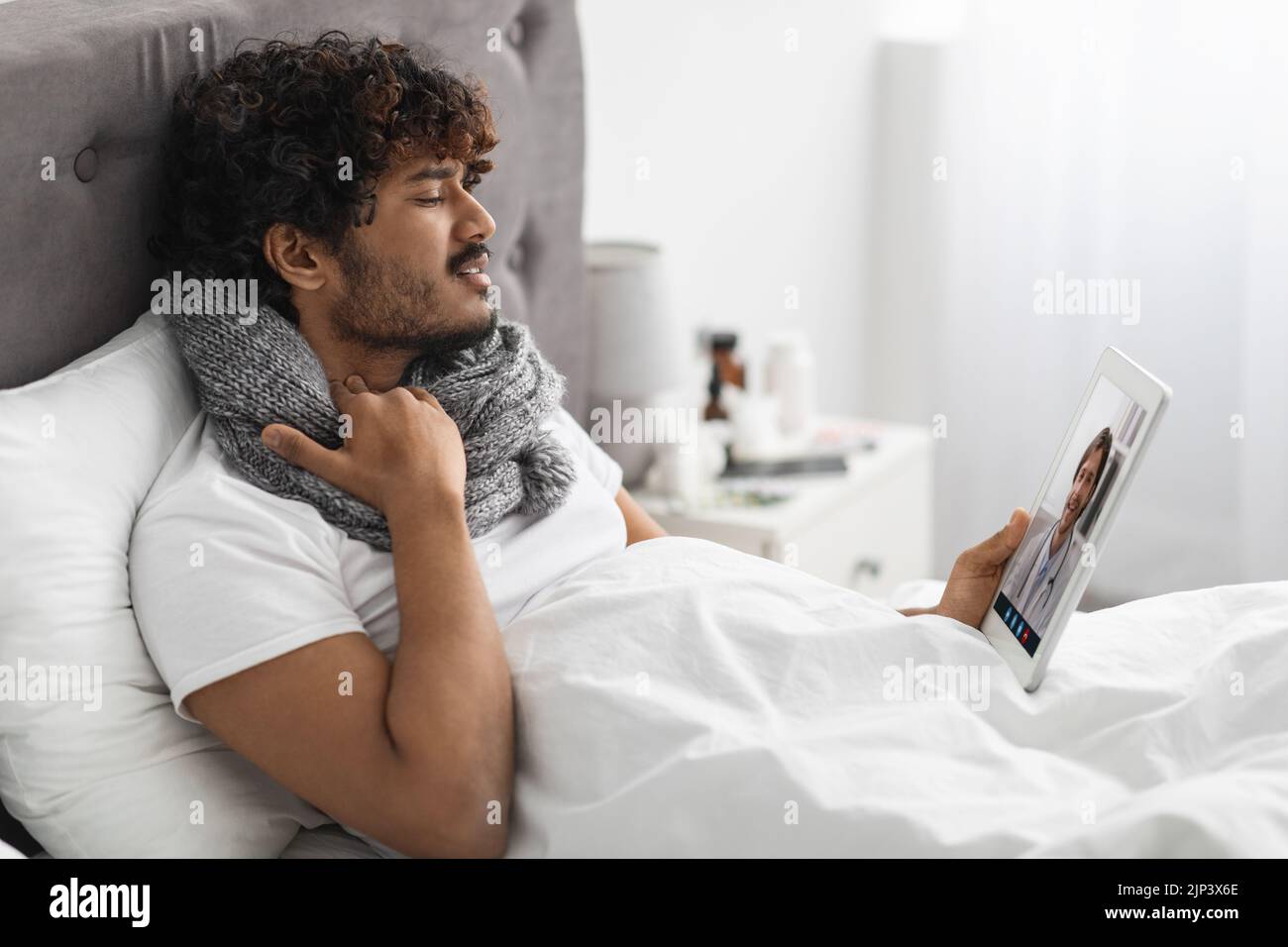 Guy having video call with doctor while staying in bed Stock Photo