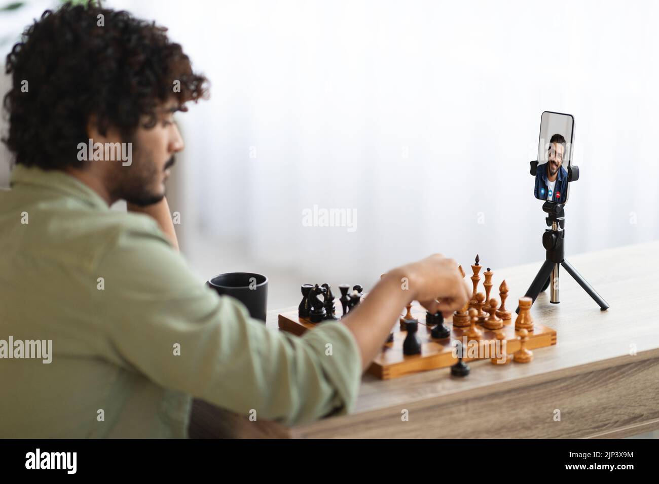 Eastern man playing chess with his friend via video call Stock Photo