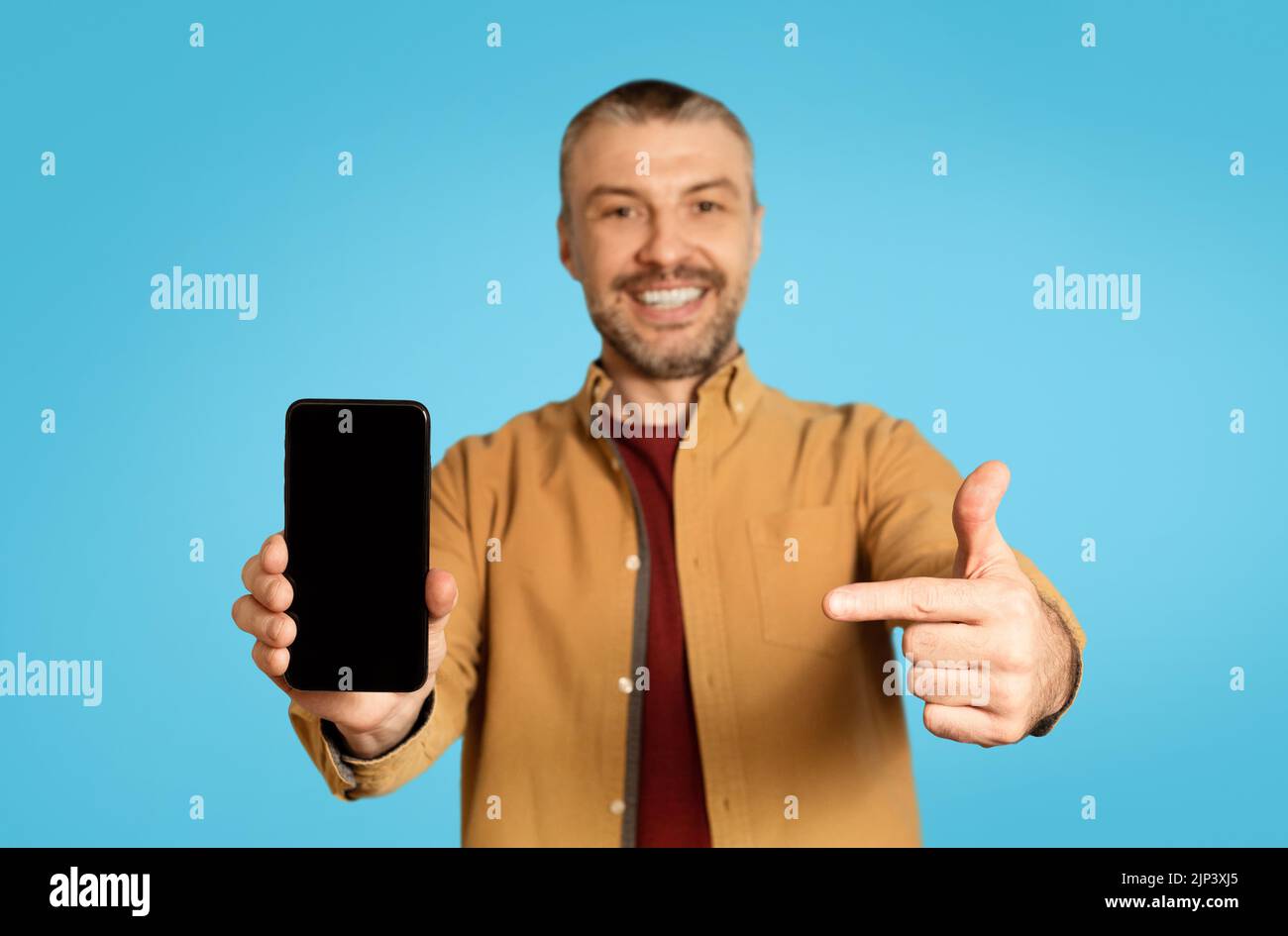 Happy Middle Aged Male Showing Smartphone Screen Over Blue Background Stock Photo