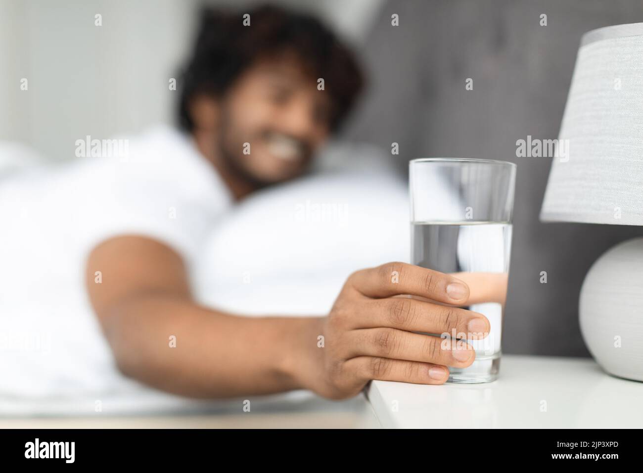 Selective focus on glass of water by eastern guy bed Stock Photo