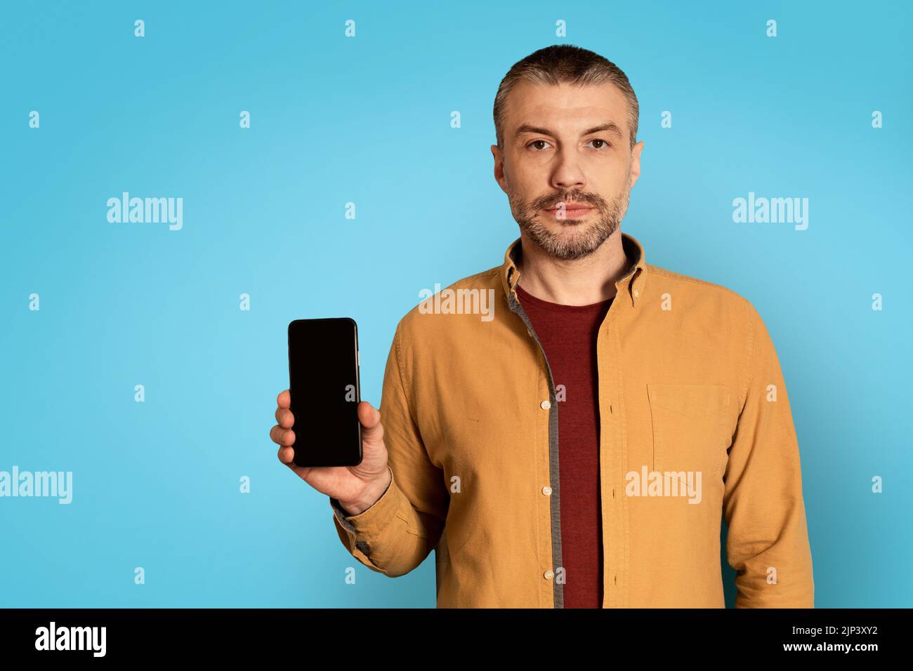 Serious Man Showing Smartphone With Empty Screen On Blue Background Stock Photo