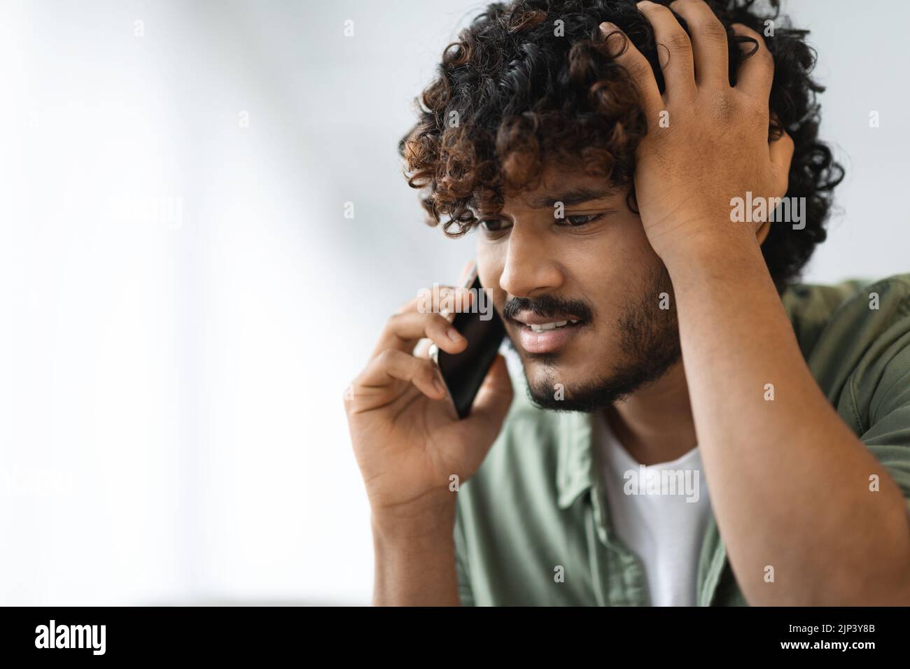 Worried eastern man having phone conversation, closeup Stock Photo