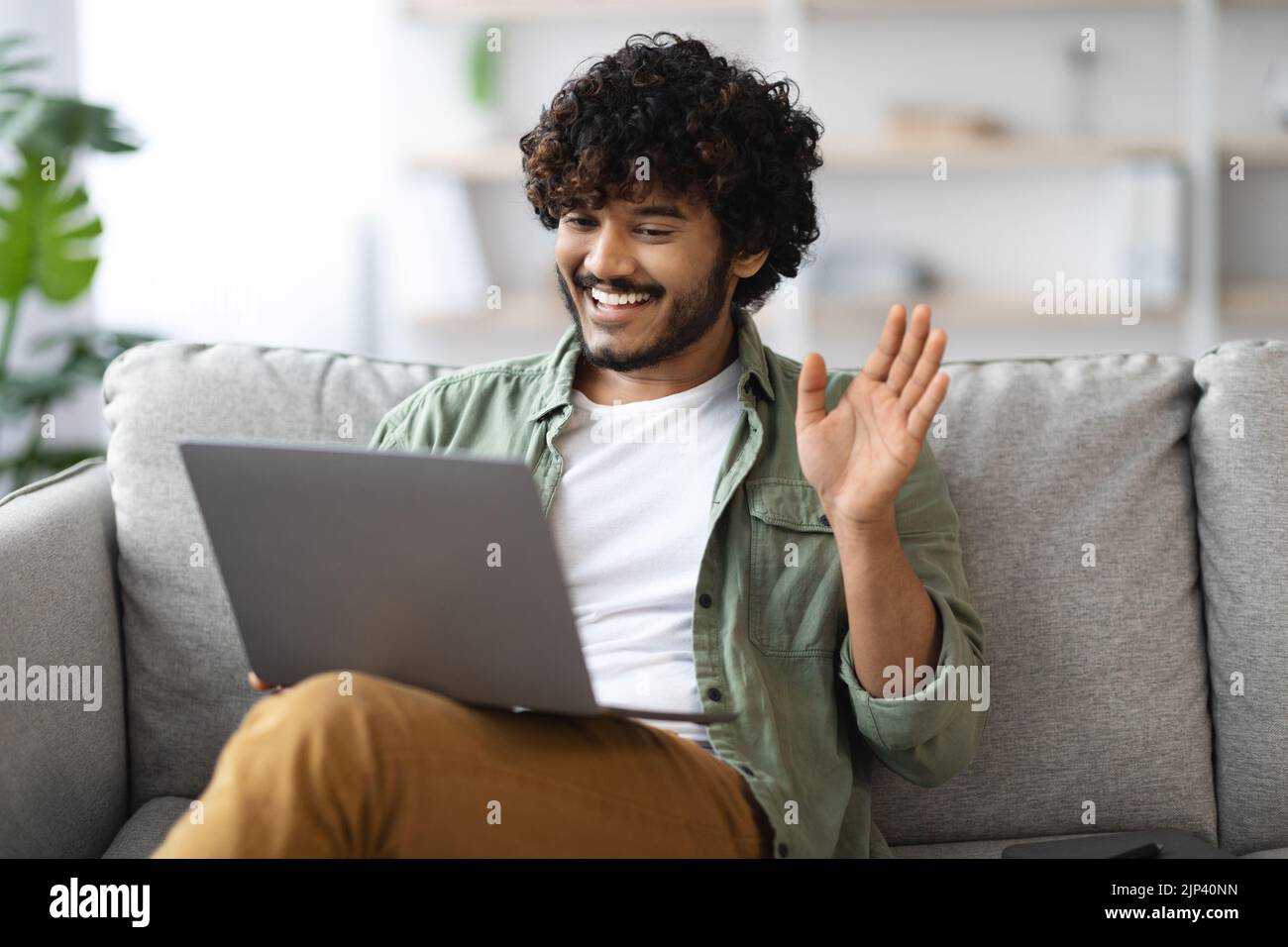 Positive eastern guy having video call, using computer at home Stock ...