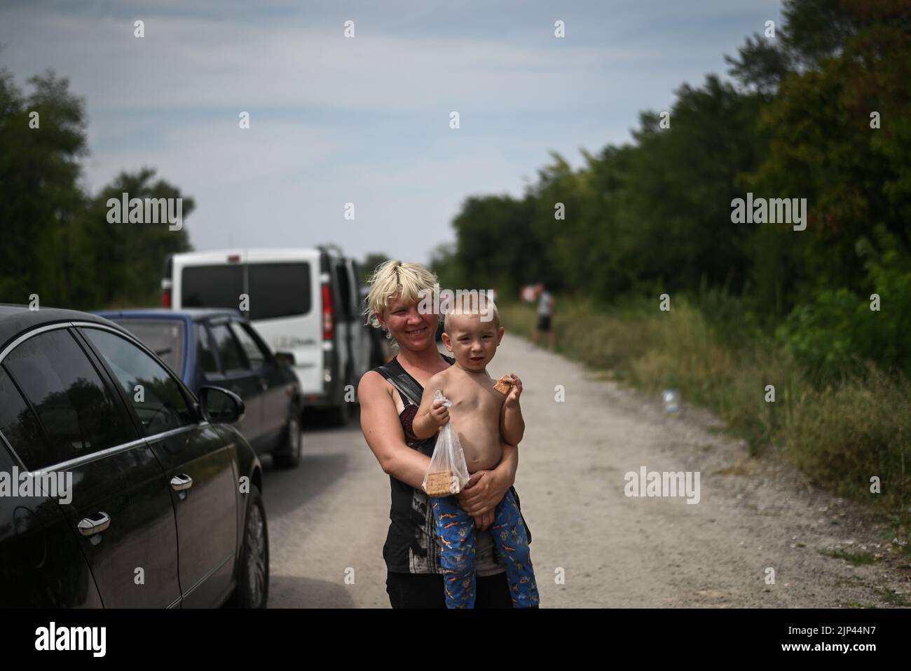 Ukraine. 14th Aug, 2022. An internally displaced person poses with her child while waiting for permission to enter Ukrainian held territory. A convoy of Internally displaced Ukrainians wait at the first Ukrainian checkpoint to cross into Ukrainian held territory South of the Ukrainian city of Zaporizhzhia on August 14, 2022. Ukraine, Zaporizhzhia. (Photo by Justin Yau/ Credit: Sipa USA/Alamy Live News Stock Photo