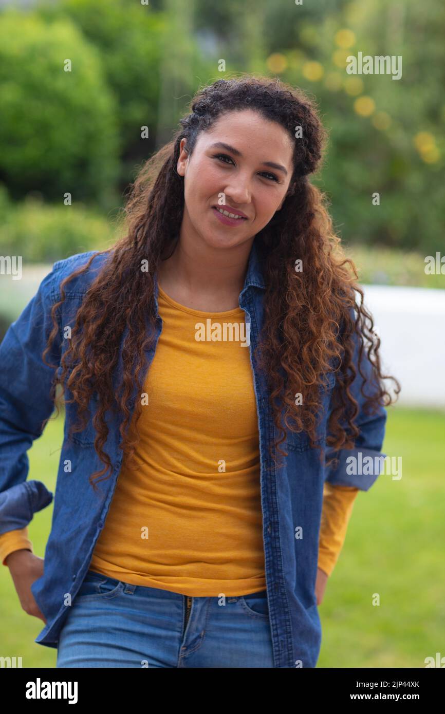 Portrait of happy biracial woman with long curly hair smiling to camera