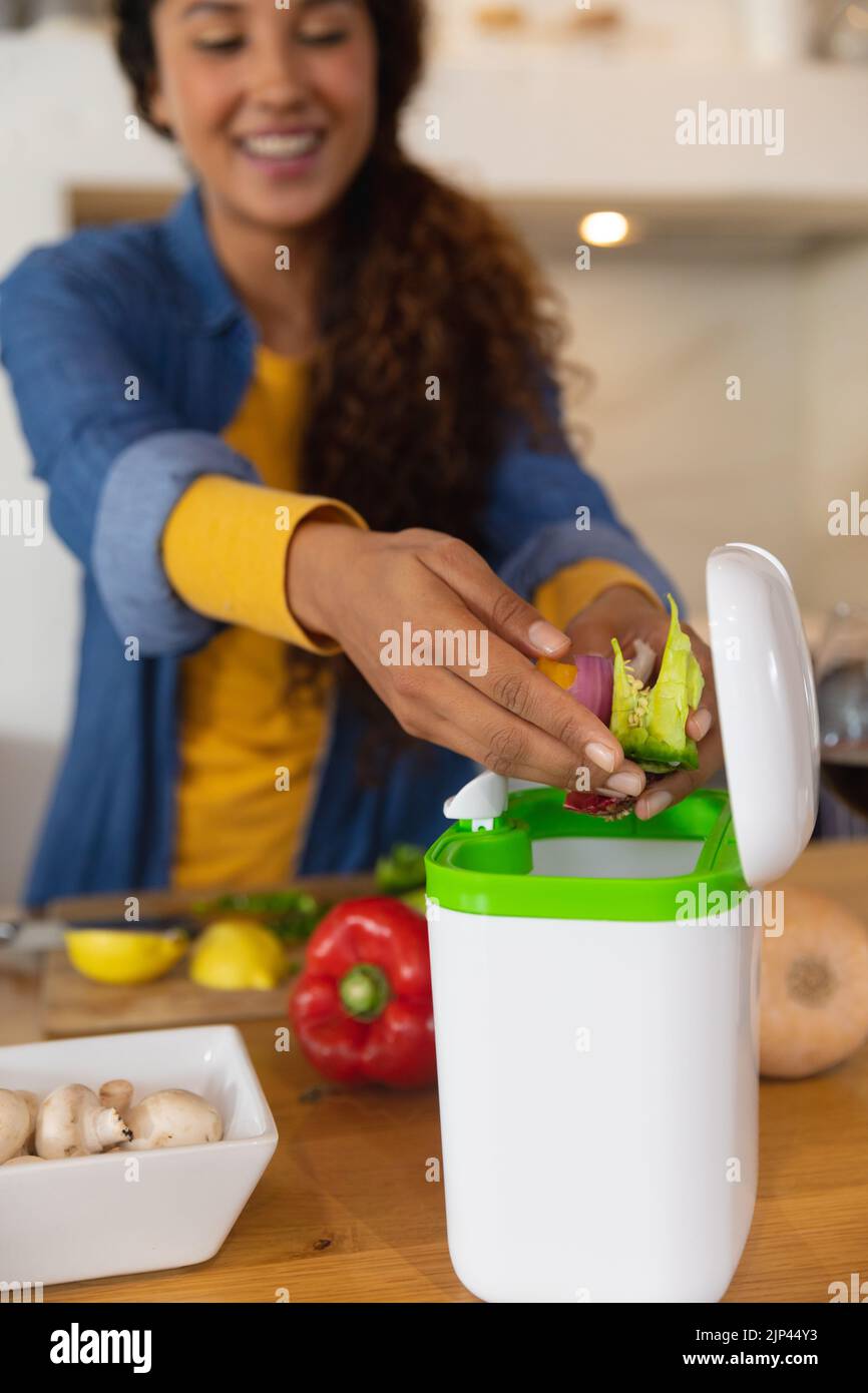 Happy biracial woman preparing food composting vegetable waste in kitchen Stock Photo