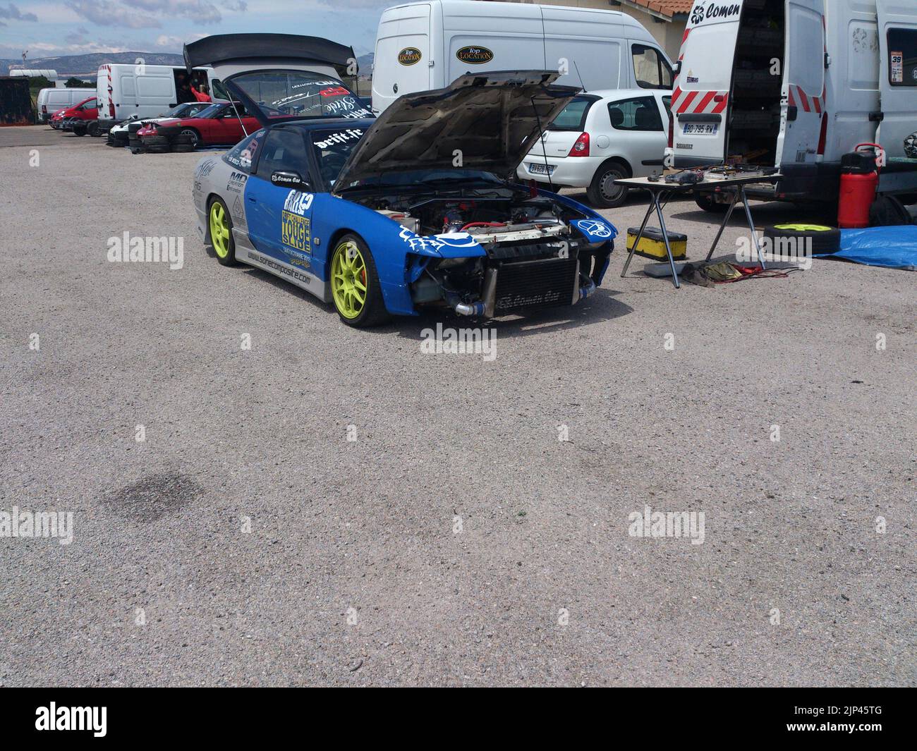 A blue sports car standing in the paddock, trunk and bonnet open Stock Photo