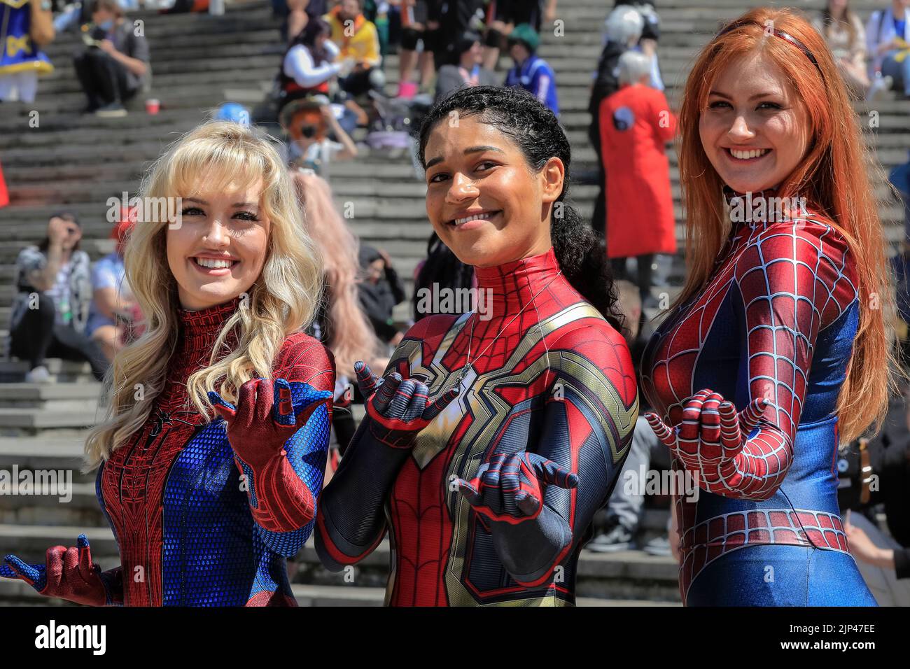 Three girls in spider woman outfit, female cosplayers in costume, smiling at camera, close up, Comic Con London Stock Photo