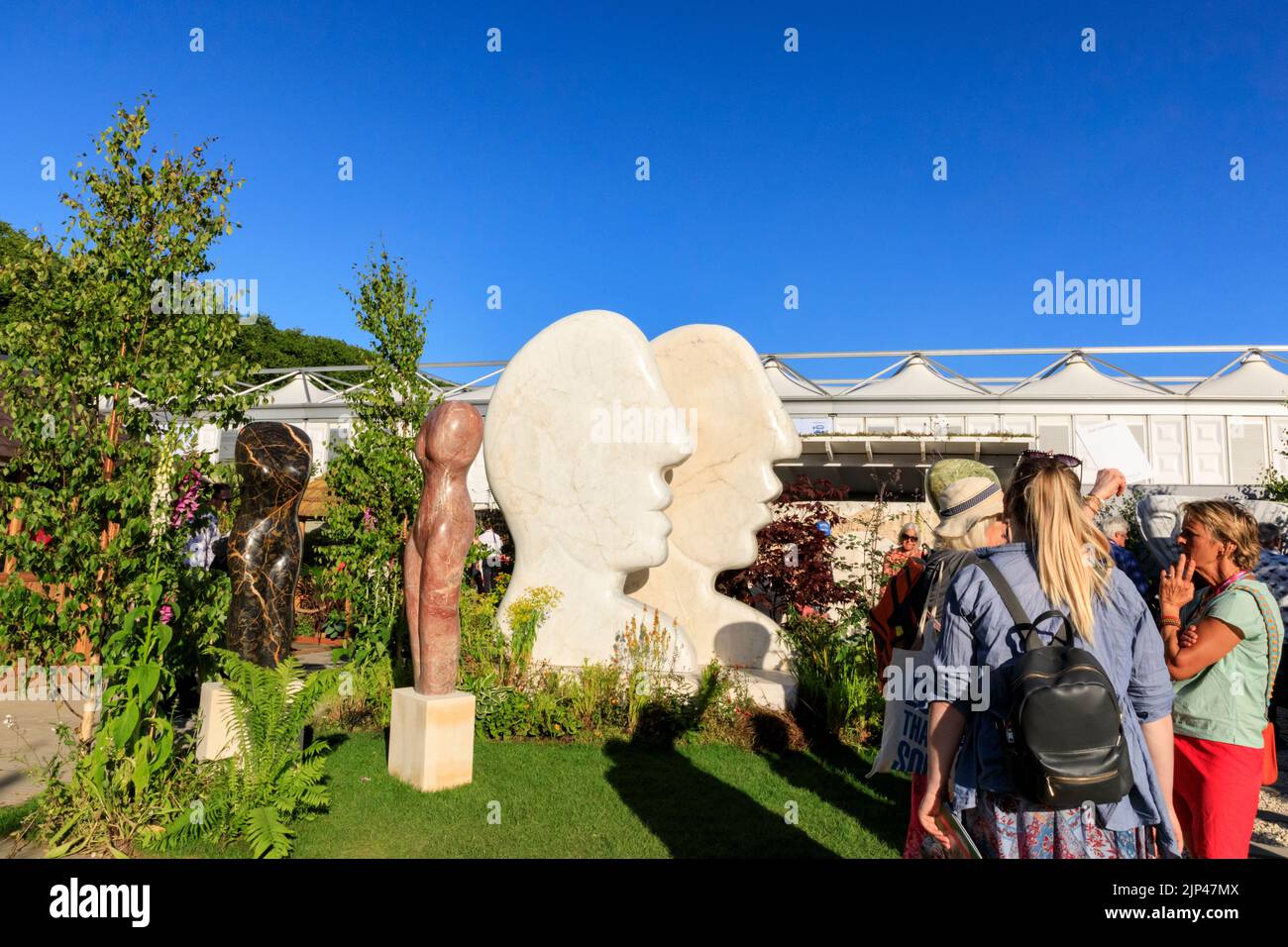 People look at marble sculptures by Paul Vanstone of torsos and the 'Kissing Profiles' head sculpture garden, Chelsea Flower Show 2022, London Stock Photo