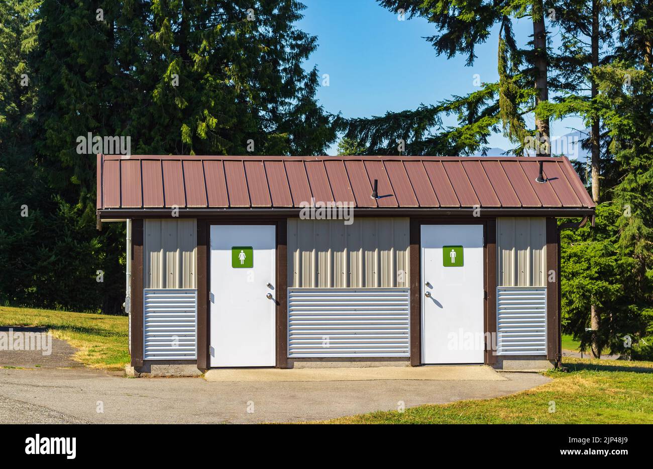 Public toilet in park at sunny summer day. Wooden restroom or toilet