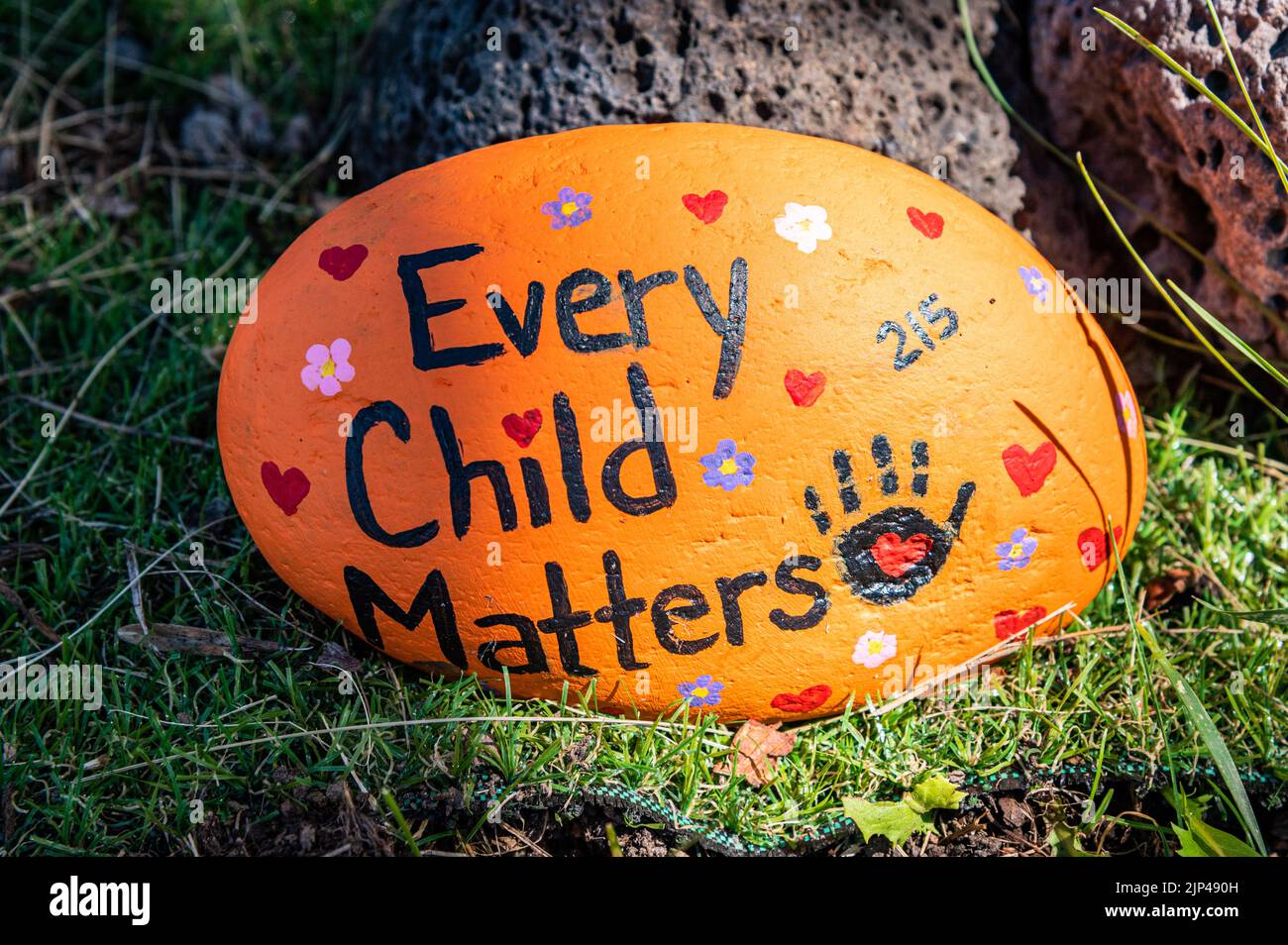 A handpainted rock that says 'Every Child Matters' on the ground against a tree at the Kamloops Residential School.  Unmarked remains have been found Stock Photo