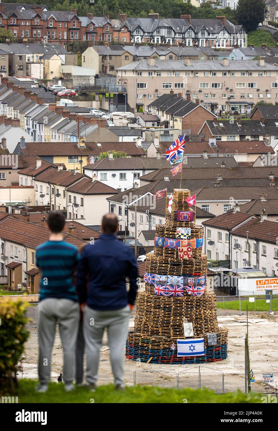 NOTE LANGUAGE ON BANNER People view a bonfire stack prior to it being lit to mark the Catholic Feast of the Assumption in the Bogside area of Londonderry, Northern Ireland. Picture date: Monday August 15, 2022. Stock Photo