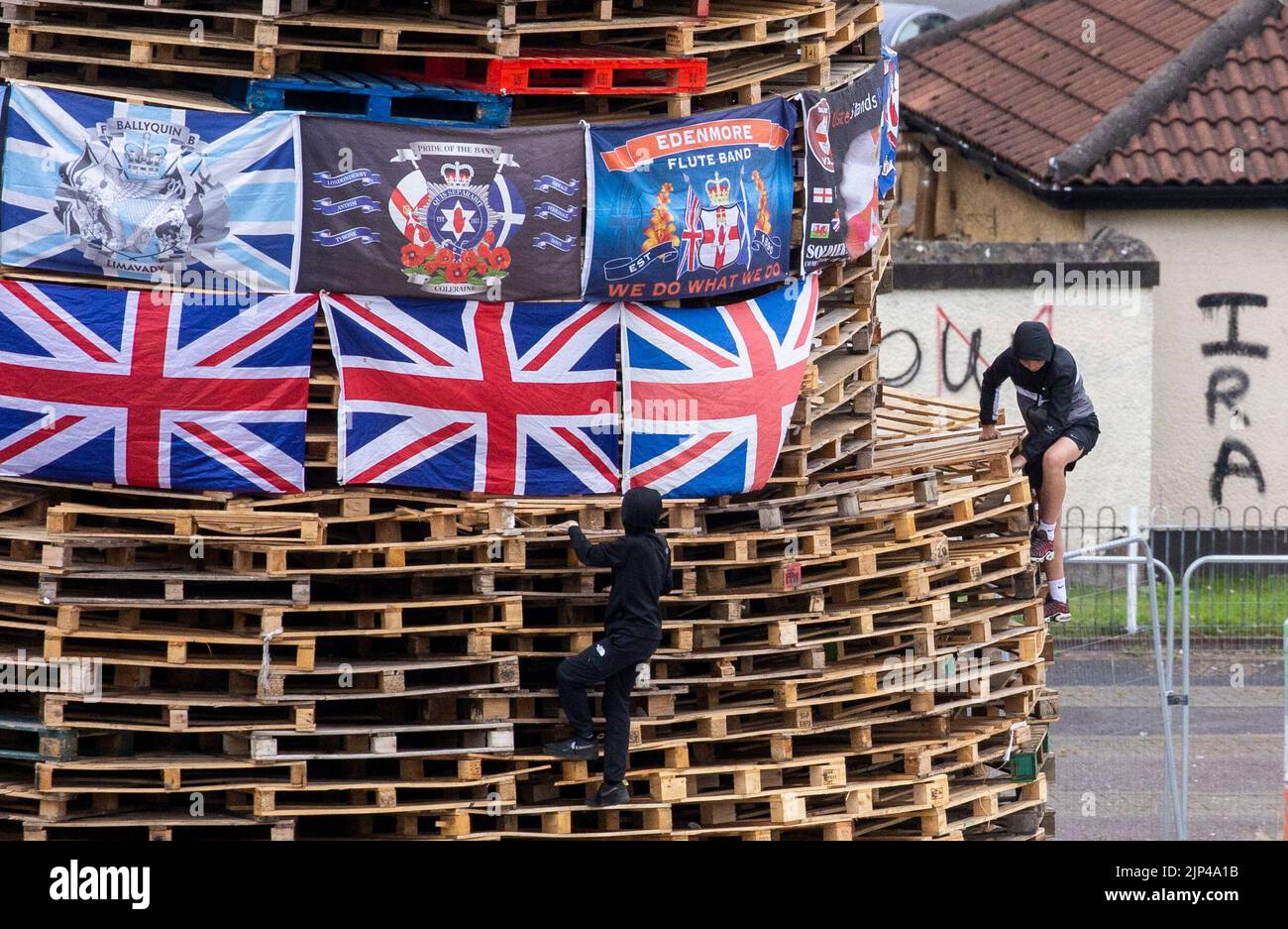 Young boys climb around a bonfire prior to it being lit to mark the Catholic Feast of the Assumption in the Bogside area of Londonderry, Northern Ireland. Picture date: Monday August 15, 2022. Stock Photo