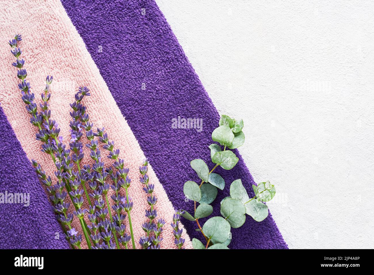 Lavender flowers, a green eucalyptus branch and fluffy towels on the light background. SPA, wellness well-being, body care concept. Copy space Stock Photo