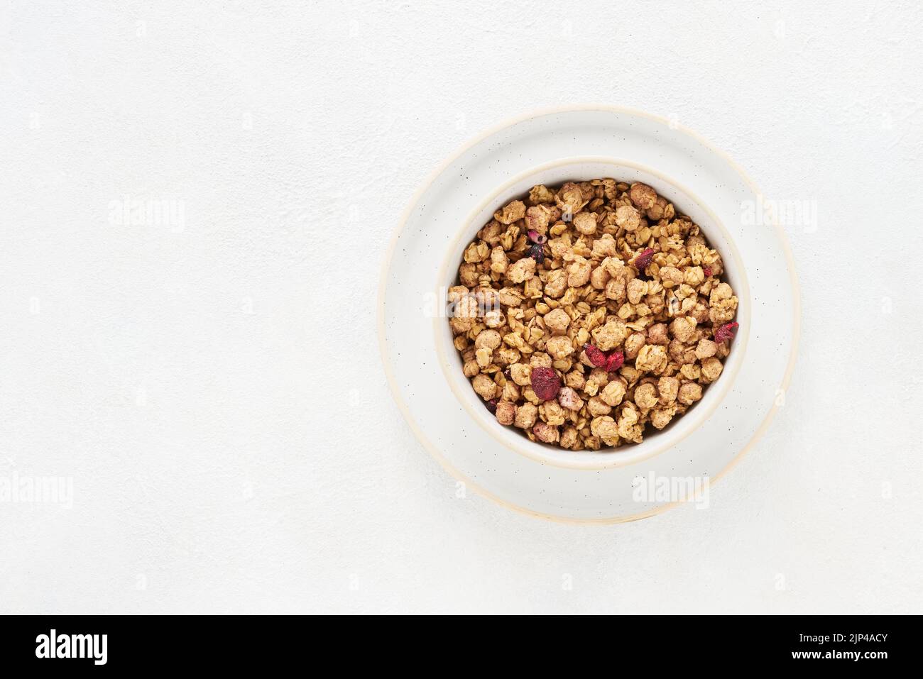 Organic wholegrain granola or crunchy muesli with dried berries in a bowl on white concrete background. Top view, copy space for text Stock Photo