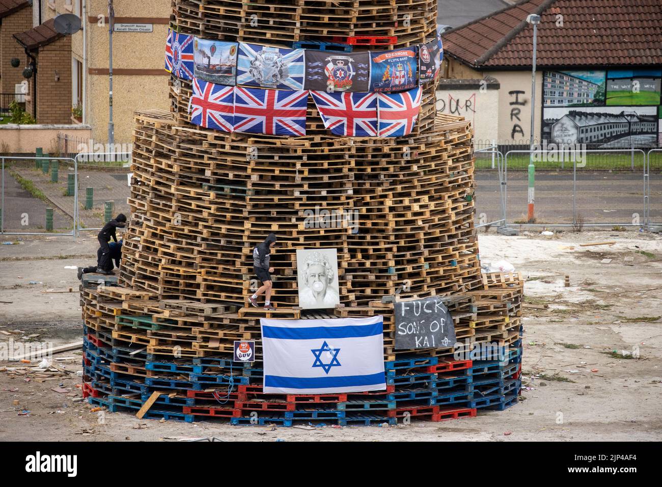 NOTE LANGUAGE ON BANNER Young boys climb around a bonfire prior to it being lit to mark the Catholic Feast of the Assumption in the Bogside area of Londonderry, Northern Ireland. Picture date: Monday August 15, 2022. Stock Photo