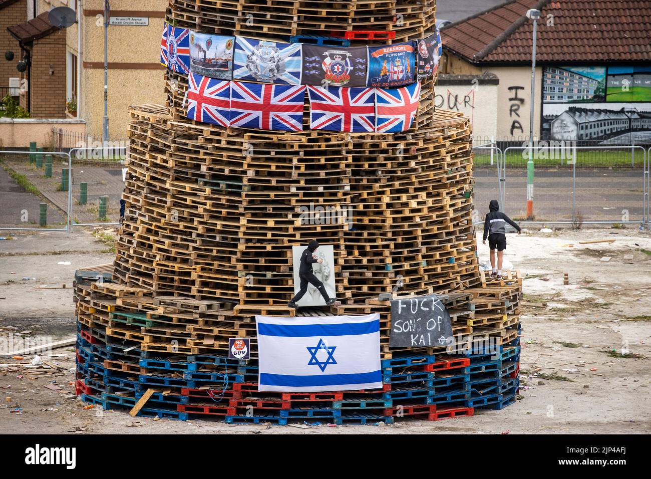 NOTE LANGUAGE ON BANNER Young boys climb around a bonfire prior to it being lit to mark the Catholic Feast of the Assumption in the Bogside area of Londonderry, Northern Ireland. Picture date: Monday August 15, 2022. Stock Photo