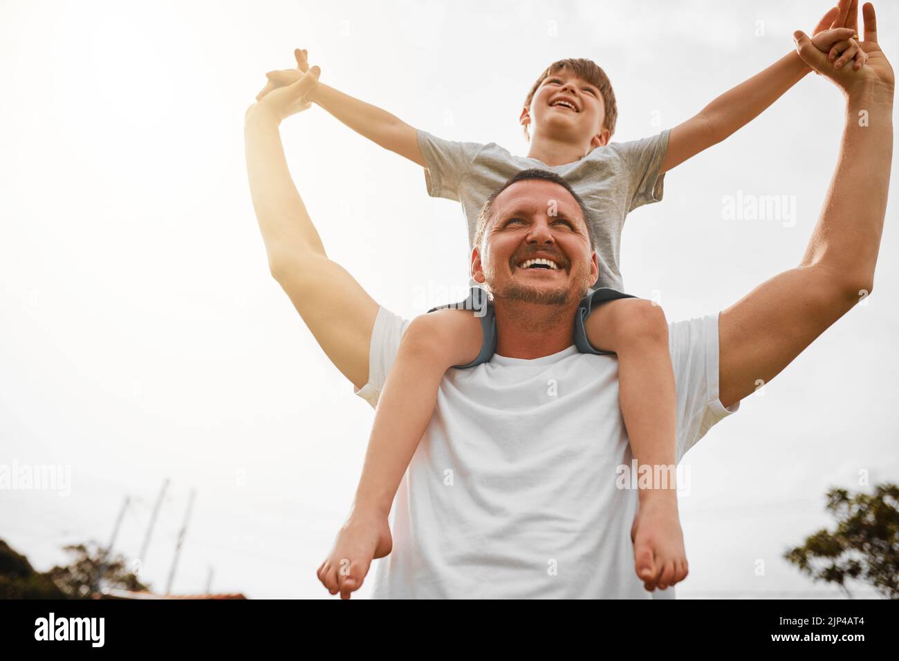 Riding high on dads shoulders. Low angle shot of a mature man carrying his young son on his shoulders outside. Stock Photo