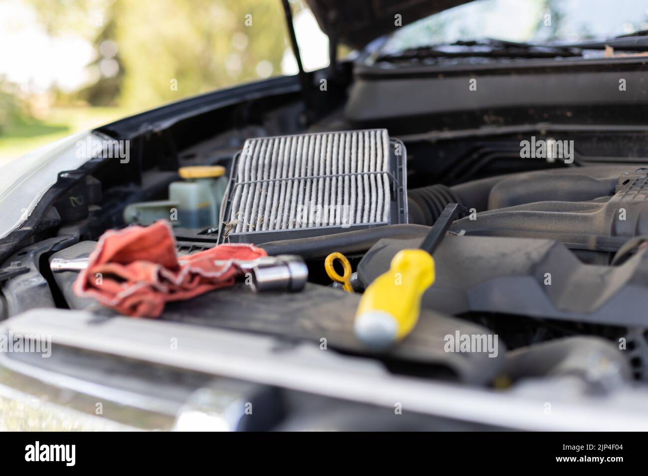 A closeup shot of a screwdriver and a cloth in an open car hood Stock