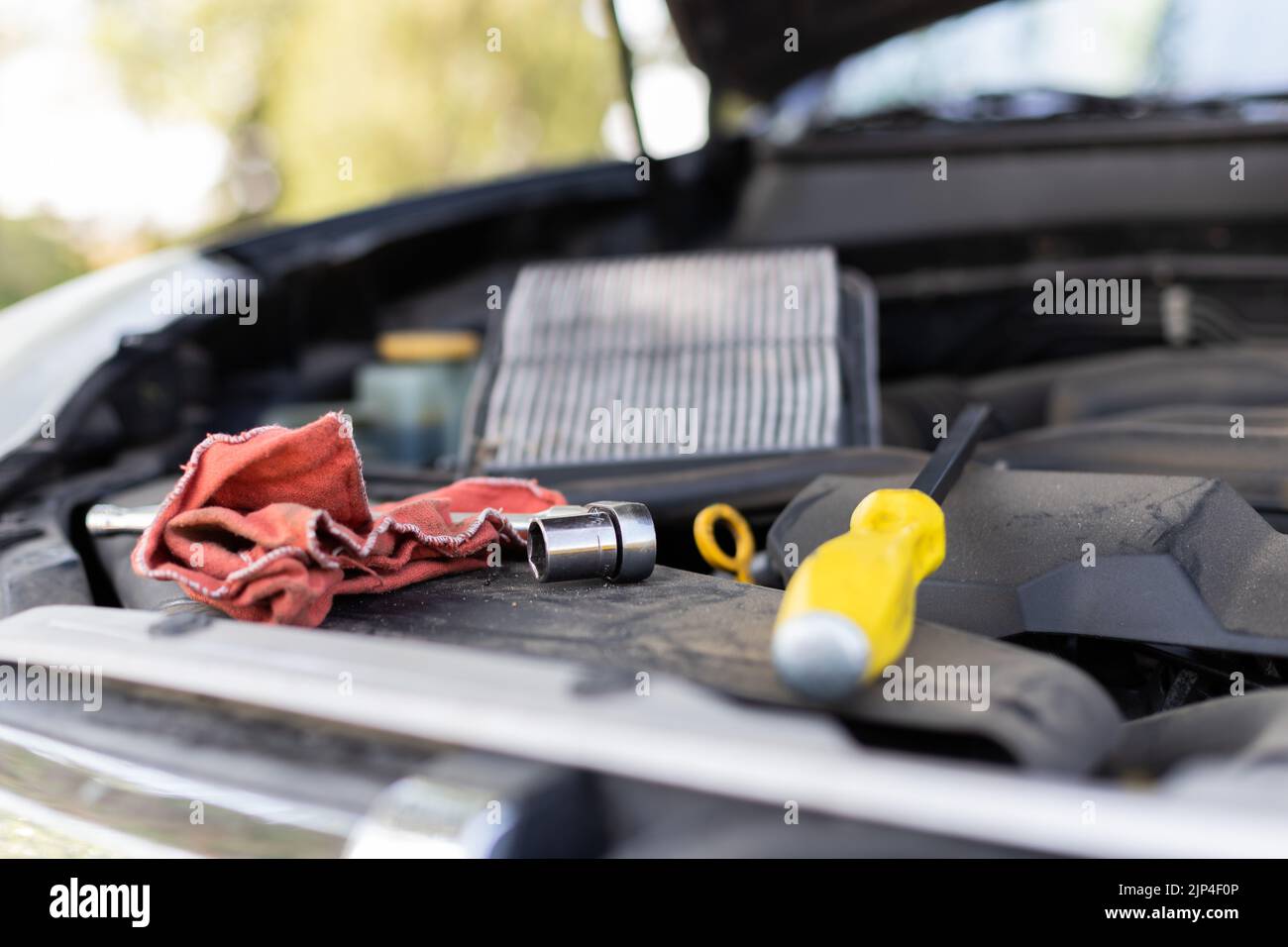 A closeup shot of a screwdriver and a cloth in an open car hood Stock