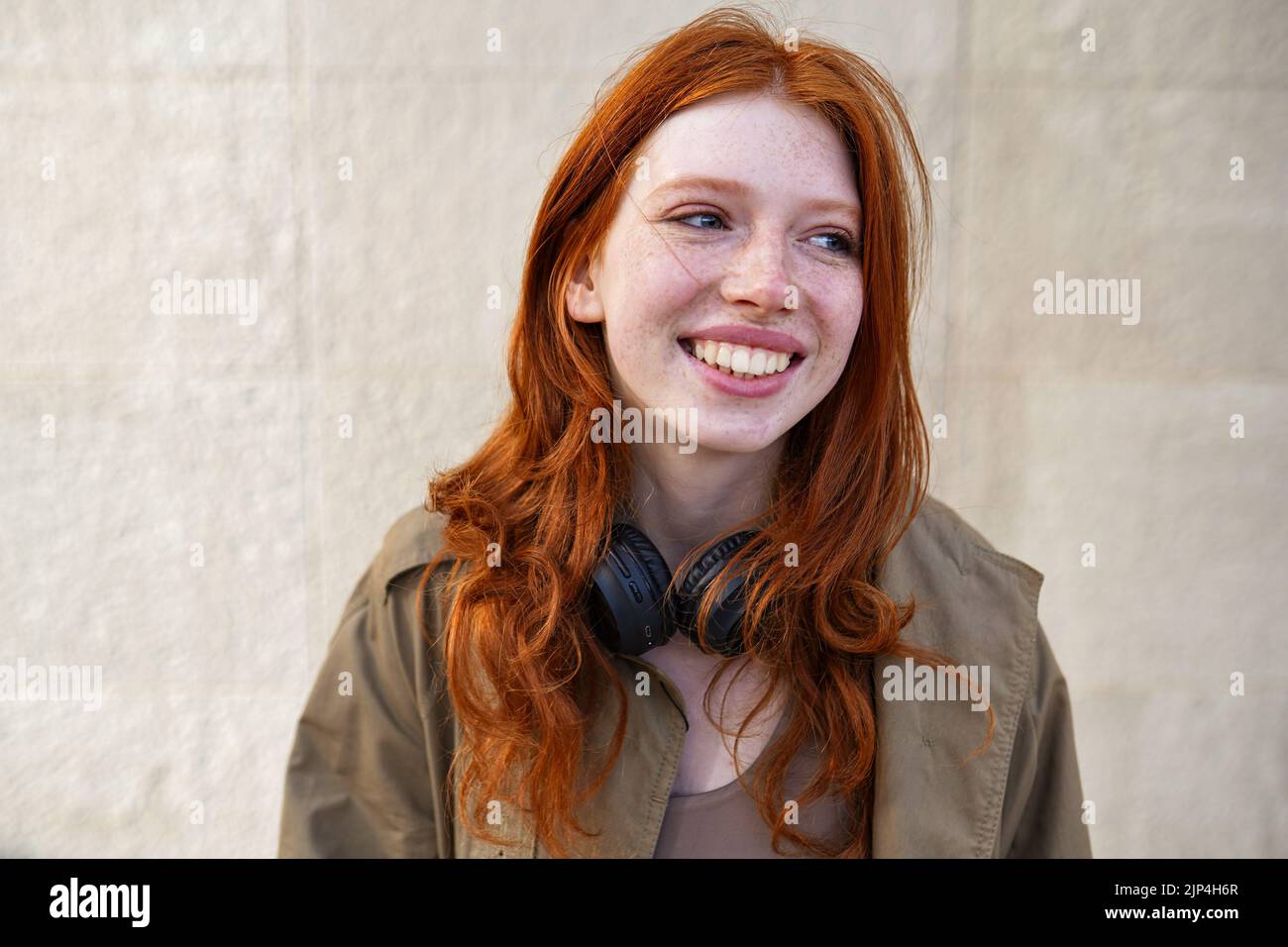 Happy teen redhead girl laughing standing on urban wall background. Stock Photo